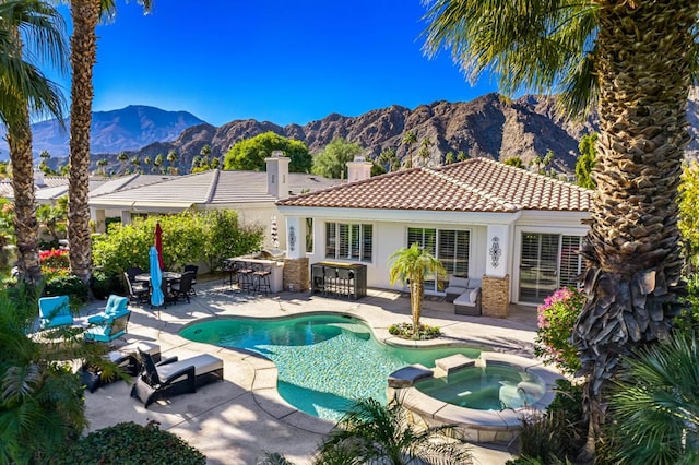 view of swimming pool with a mountain view, a patio area, an in ground hot tub, and exterior bar