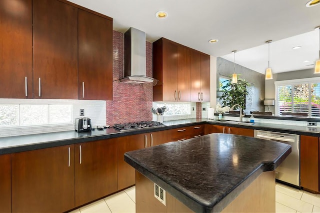 kitchen with pendant lighting, sink, appliances with stainless steel finishes, tasteful backsplash, and wall chimney exhaust hood