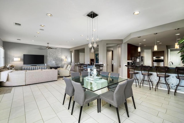 tiled dining room with ceiling fan and sink