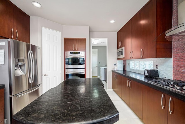 kitchen with tasteful backsplash, appliances with stainless steel finishes, light tile patterned floors, and dark stone counters