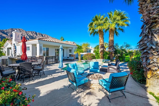 view of patio with a mountain view and an outdoor living space with a fire pit