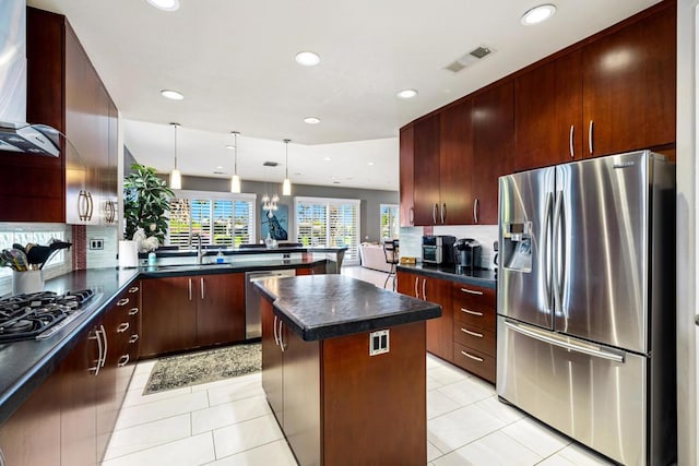 kitchen with pendant lighting, sink, appliances with stainless steel finishes, a center island, and kitchen peninsula