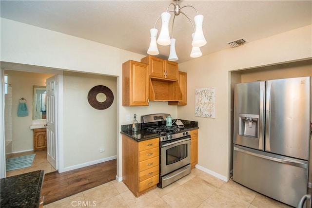 kitchen featuring light hardwood / wood-style flooring, a notable chandelier, dark stone countertops, pendant lighting, and appliances with stainless steel finishes