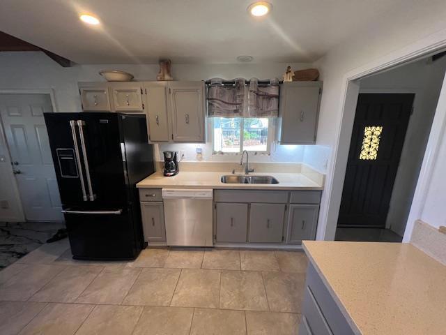 kitchen featuring light tile patterned floors, gray cabinetry, black fridge with ice dispenser, stainless steel dishwasher, and sink