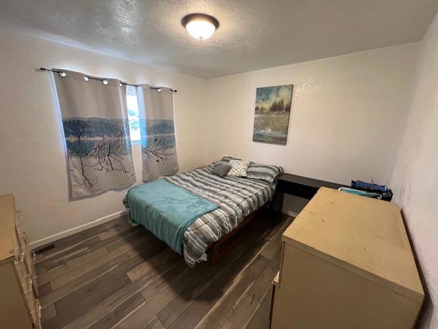 bedroom with dark wood-type flooring and a textured ceiling