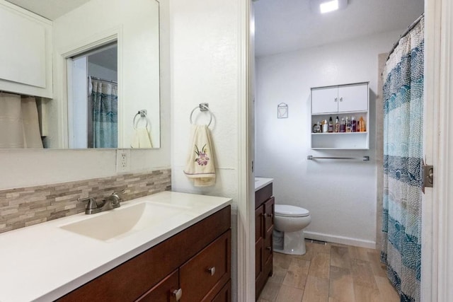 bathroom featuring hardwood / wood-style flooring, toilet, vanity, and tasteful backsplash