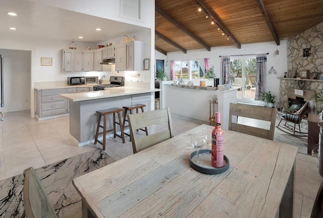 tiled dining room featuring wood ceiling, a fireplace, and vaulted ceiling with beams