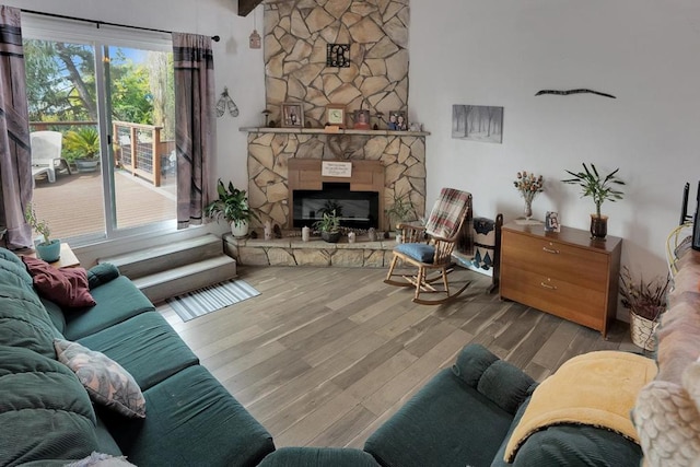 living room with hardwood / wood-style floors, a stone fireplace, and beamed ceiling