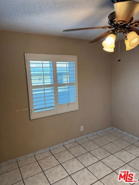 tiled spare room with ceiling fan and a textured ceiling