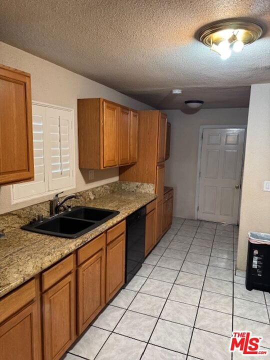 kitchen with light stone countertops, a textured ceiling, sink, light tile patterned floors, and dishwasher