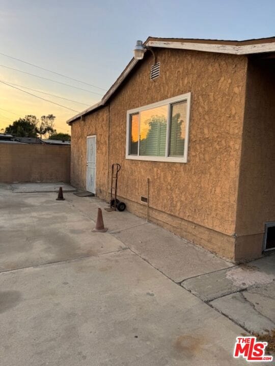 property exterior at dusk featuring a patio