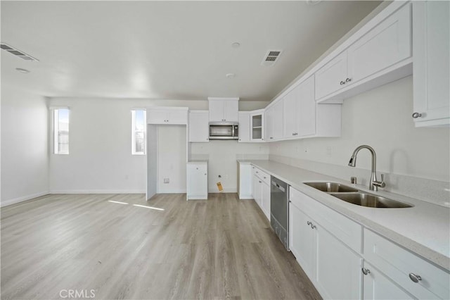 kitchen with white cabinets, appliances with stainless steel finishes, light hardwood / wood-style floors, and sink