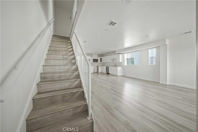 stairs with baseboards, visible vents, and wood finished floors