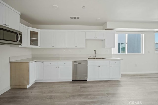 kitchen featuring white cabinetry, sink, stainless steel appliances, and light hardwood / wood-style flooring