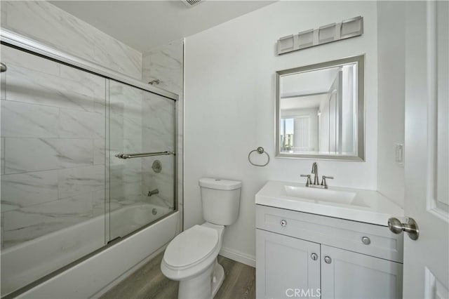 full bathroom featuring hardwood / wood-style floors, vanity, toilet, and enclosed tub / shower combo