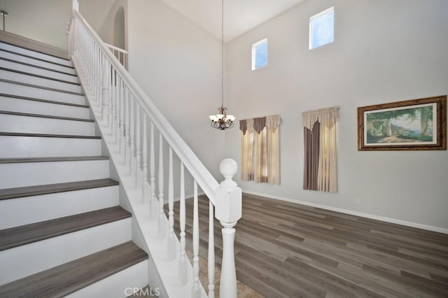 stairs featuring a high ceiling, hardwood / wood-style flooring, and a notable chandelier