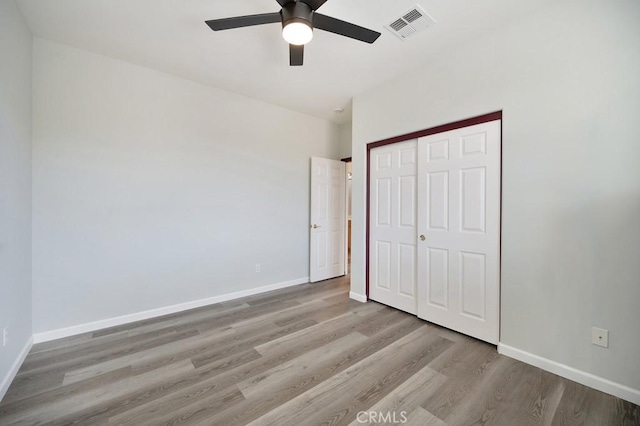 unfurnished bedroom featuring a closet, light hardwood / wood-style flooring, and ceiling fan