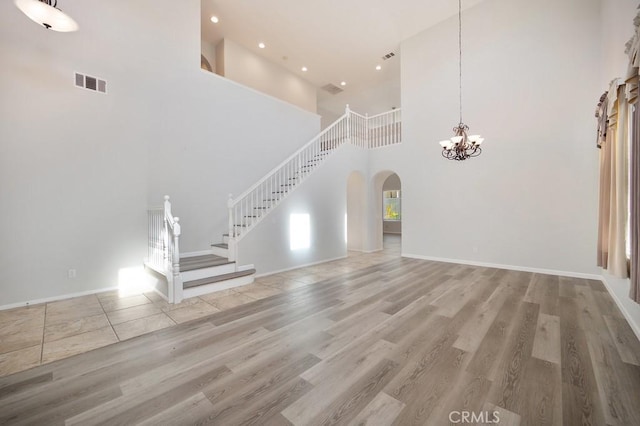 unfurnished living room with a towering ceiling and light wood-type flooring