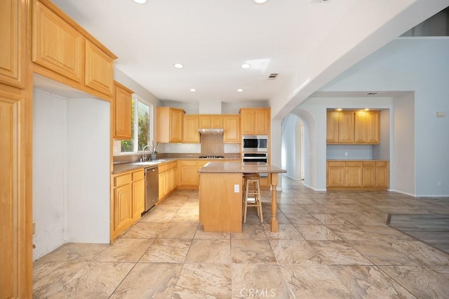 kitchen featuring sink, a center island, a breakfast bar area, light brown cabinetry, and appliances with stainless steel finishes