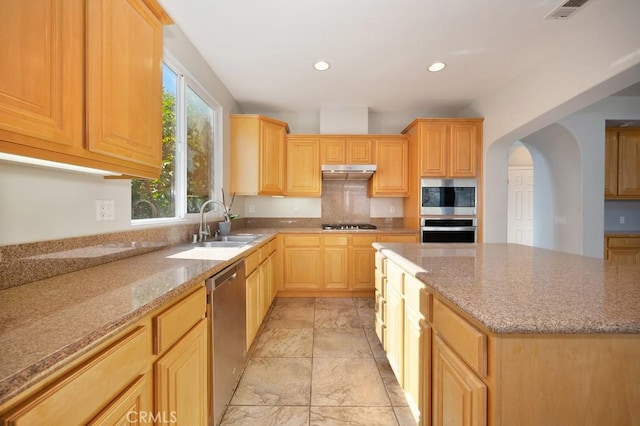 kitchen featuring light brown cabinets, sink, a kitchen island, light stone counters, and stainless steel appliances