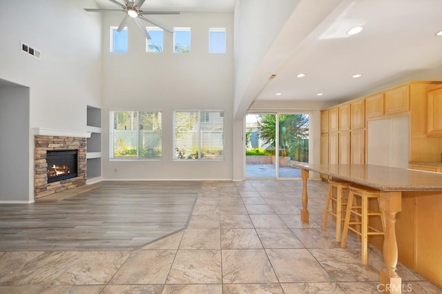 unfurnished living room with ceiling fan, a fireplace, a wealth of natural light, and light hardwood / wood-style flooring