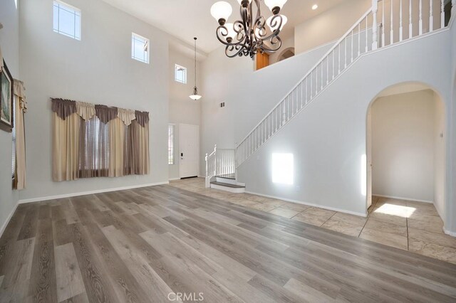 unfurnished living room featuring a chandelier, a high ceiling, and hardwood / wood-style flooring