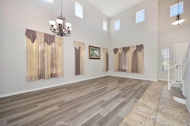 interior space featuring a notable chandelier, wood-type flooring, and a towering ceiling