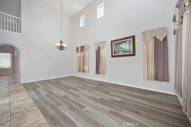 empty room with a high ceiling, hardwood / wood-style flooring, and a notable chandelier