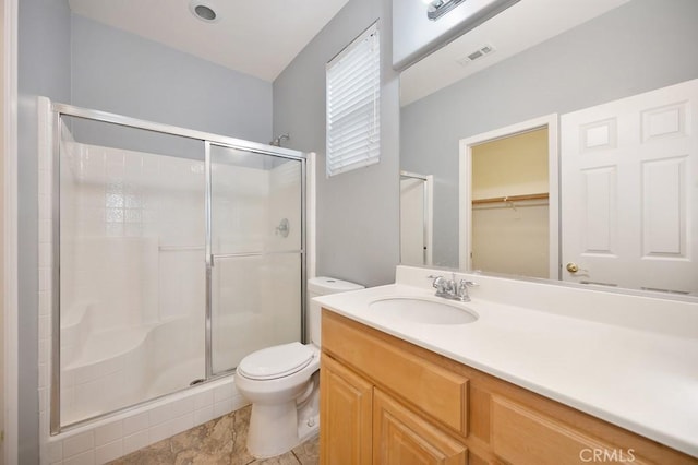 bathroom featuring tile patterned floors, vanity, toilet, and a shower with shower door