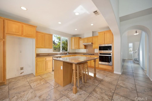 kitchen featuring a kitchen island, a breakfast bar area, and light brown cabinets