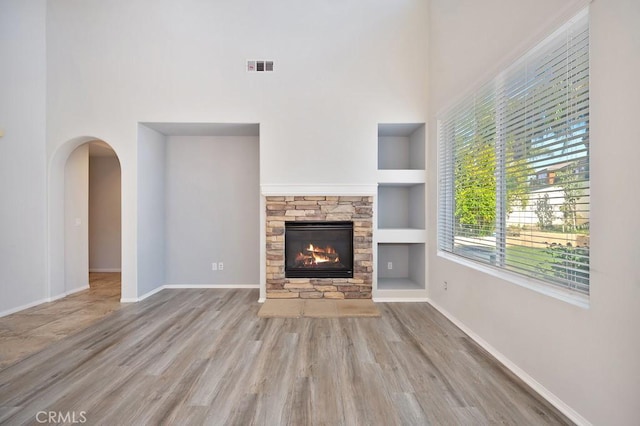 unfurnished living room featuring a fireplace, built in features, and hardwood / wood-style floors