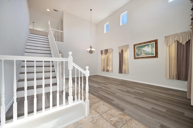 stairs featuring hardwood / wood-style flooring, a high ceiling, and a chandelier