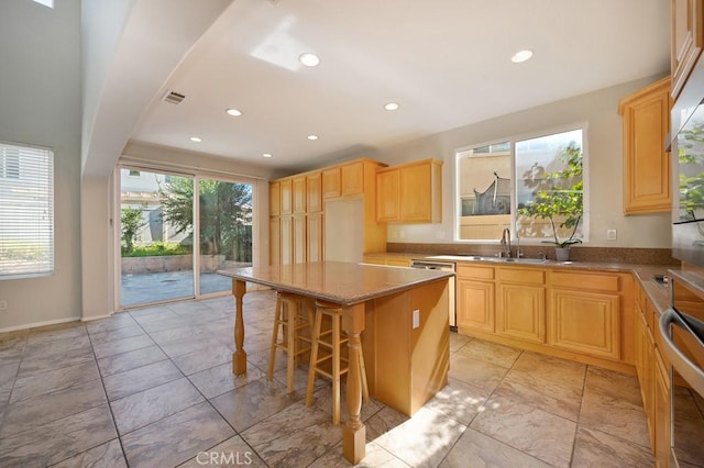 kitchen with a center island, a kitchen bar, sink, and a wealth of natural light