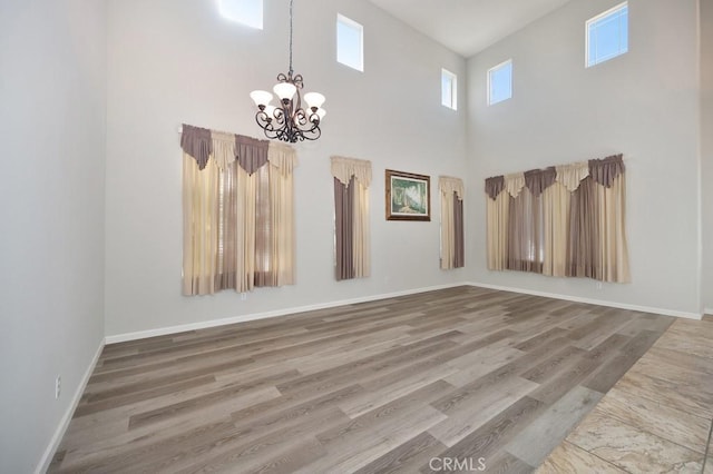 unfurnished room featuring hardwood / wood-style flooring, a notable chandelier, and a high ceiling