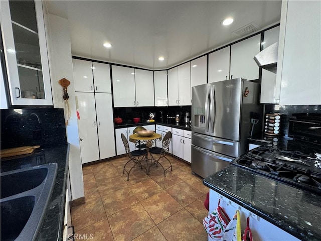 kitchen with decorative backsplash, stainless steel fridge, white cabinetry, and sink