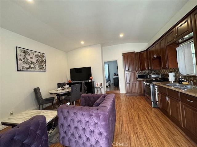 living room with lofted ceiling, sink, and light hardwood / wood-style flooring