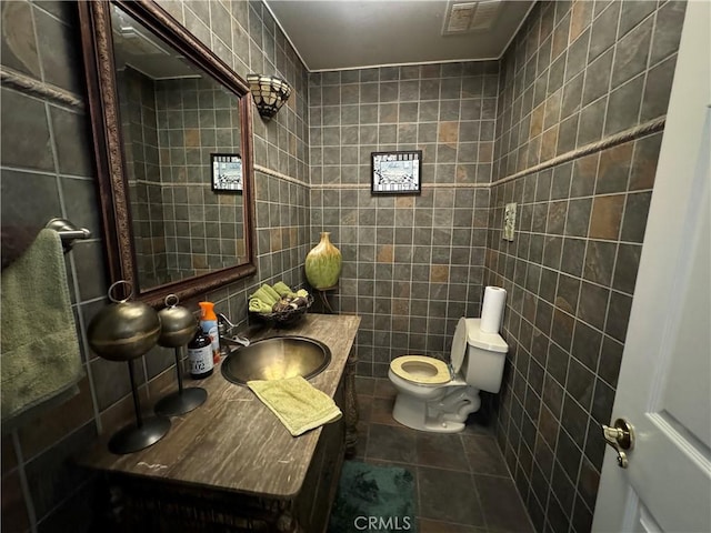 bathroom featuring toilet, sink, tile walls, and tile patterned flooring