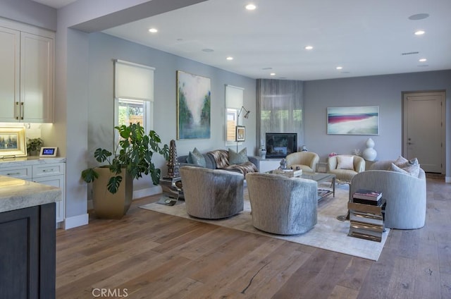 living room featuring light wood-type flooring and a large fireplace