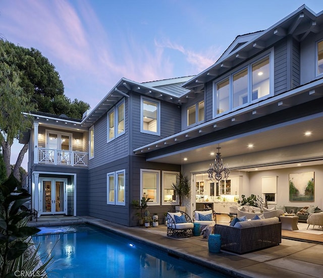 back house at dusk featuring a patio, outdoor lounge area, and french doors