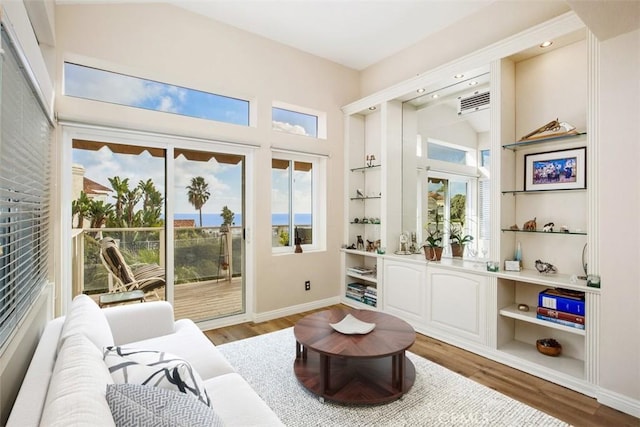 sitting room featuring hardwood / wood-style floors, built in shelves, and a healthy amount of sunlight