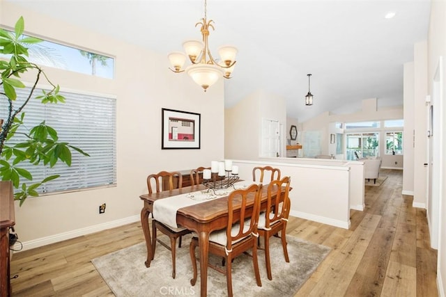 dining space with a notable chandelier, lofted ceiling, and light wood-type flooring