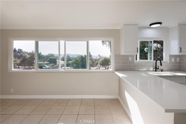 kitchen with decorative backsplash, white cabinetry, sink, and light tile patterned floors