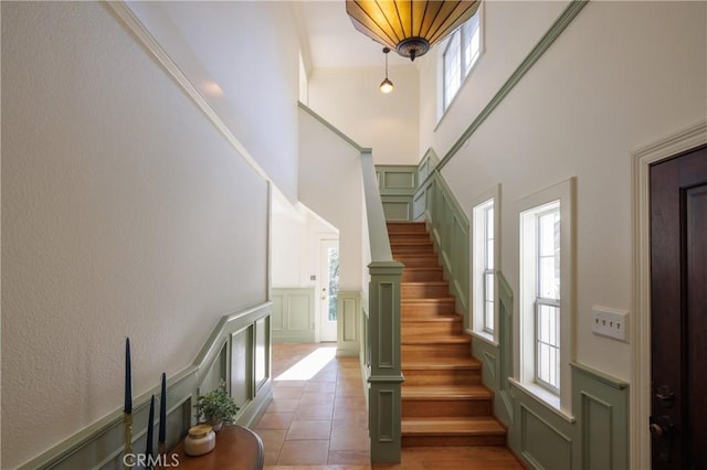 stairway featuring tile patterned floors, a towering ceiling, and ornamental molding