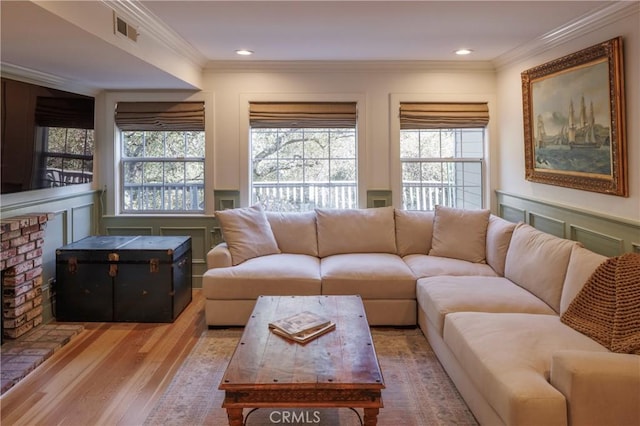 living room with hardwood / wood-style floors, a wealth of natural light, and ornamental molding