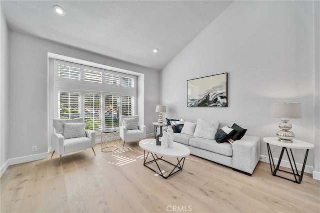 living room with light wood-type flooring and high vaulted ceiling