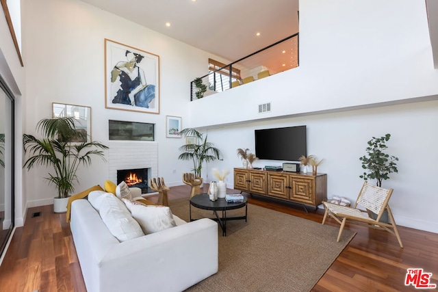 living room featuring a fireplace, a high ceiling, and dark hardwood / wood-style floors