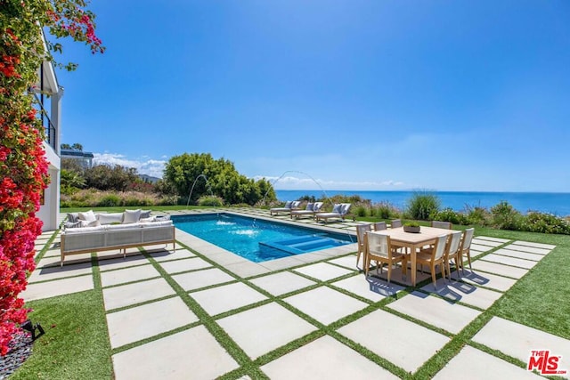 view of pool with outdoor lounge area, pool water feature, a water view, and a patio area