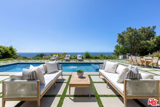 view of swimming pool featuring pool water feature, an outdoor living space, a water view, and a patio