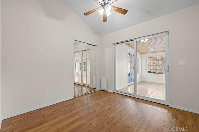 empty room featuring ceiling fan, lofted ceiling, radiator heating unit, and light hardwood / wood-style floors