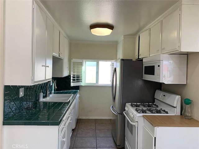 kitchen with white appliances, tile patterned flooring, a textured ceiling, white cabinets, and sink